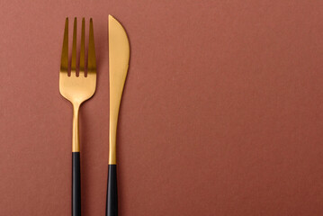 Knife and fork, cutlery on a brown dining table