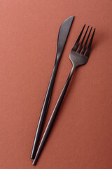 Knife and fork, cutlery on a brown dining table