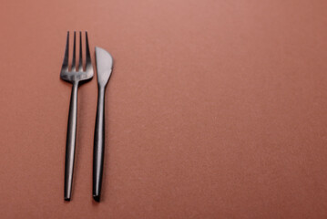 Knife and fork, cutlery on a brown dining table
