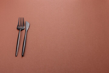 Knife and fork, cutlery on a brown dining table