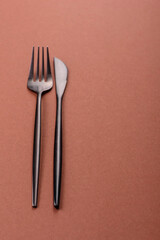 Knife and fork, cutlery on a brown dining table