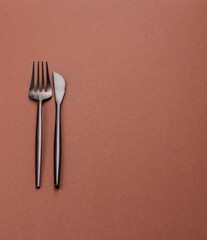 Knife and fork, cutlery on a brown dining table