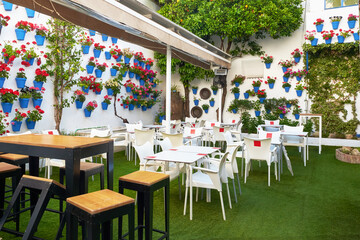 Outdoor cafe with flowers in a Cordoba, Spain. Flowers in a blue pots on a white wall.