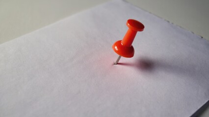 A small red paperclip on a white piece of paper.