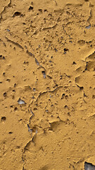 Cracked yellow stucco wall with holes