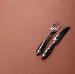Knife and fork, cutlery on a brown dining table