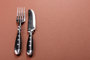 Knife and fork, cutlery on a brown dining table