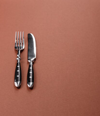 Knife and fork, cutlery on a brown dining table
