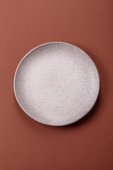 Empty ceramic plate on a monochrome brown background