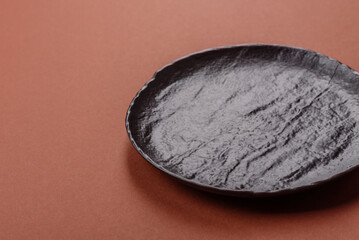 Empty ceramic plate on a monochrome brown background