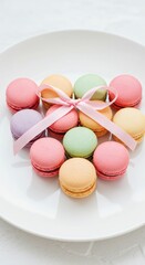 Fototapeta premium Pastel macarons arranged in heart shape on white plate with ribbon.