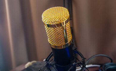 Condenser microphone with a golden metal mesh on a fabric background. Close up of a condenser...