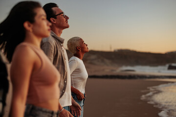 Friends enjoying breathtaking sunset view on sandy beach: