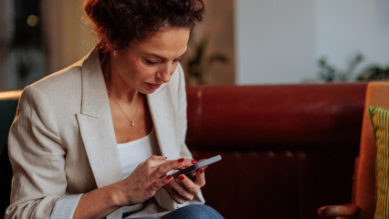 Upset businesswoman checking her phone in the lobby