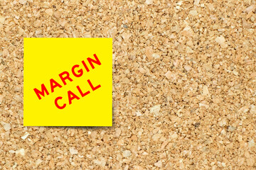 Yellow note paper with word margin call on cork board background with copy space