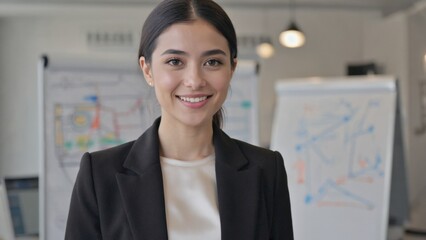 A woman in a business suit is smiling at the camera. She is standing in front of a white board with a sign that says "Engineering"