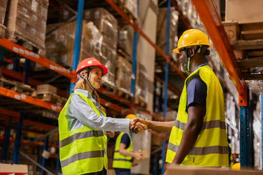 Warehouse workers shaking hands after finishing work in logistics center