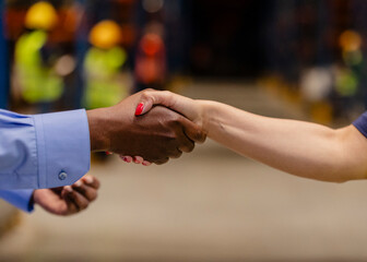 Business people shaking hands in warehouse, closing a deal