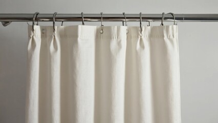 A white shower curtain hangs on a metal rod. The curtain is white and has a silver frame