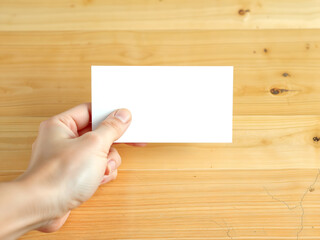 Fototapeta premium Hand holding small blank card against wooden background, ready for text or message. Generative AI