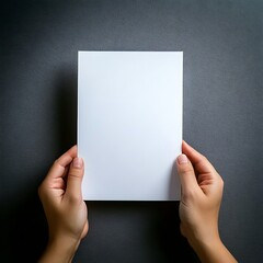 A pair of hands holding a piece of blank white A4 paper; grey background; graphic resources; graphic elements; top angle view of a pair of hands holding a blank white piece of paper; mock up photo,