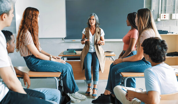 Teenager High School students talking to mature female teacher. Group support conversation in Higher Education