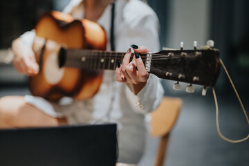 A focused view of a musician playing an acoustic guitar in a creative studio environment. The image...