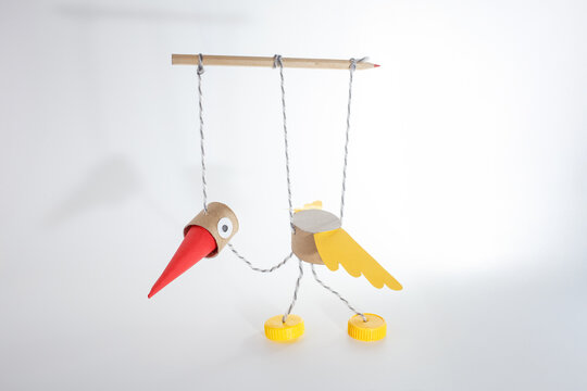 Bird marionette toy made from cardboard, paper, string, pencil and plastic caps. Handmade puppet and DIY bird craft concept for children creativity and learning