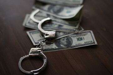 Handcuffs on Stack of Dollar Bills Symbolizing Financial Crime and Corruption