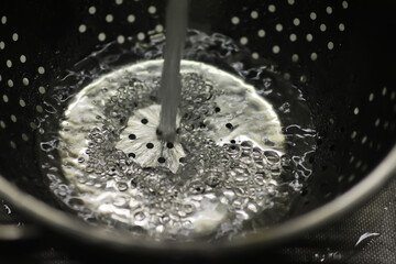 Water Pouring into Colander with Bubbles in Kitchen or Food Preparation Context