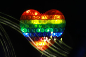Colorful Heart-Shaped Pop It Toy with Rainbow Pattern on Black Background