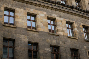 Architectural details of a historic building showcasing textured stone and a series of symmetrical windows in an urban setting