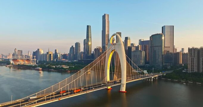 Aerial view of modern bridge and Guangzhou financial district skyline at sunrise.