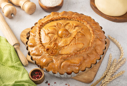 The traditional Tatar national dish is Zur-balish. A pie stuffed with beef, potatoes and onions on a table with a rolling pin, flour and a piece of dough.