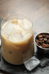 Coffee cream liqueur in glass, ice cubes and beans on table, closeup