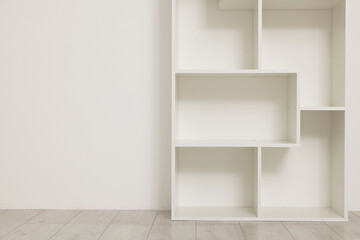 Empty shelving unit near light wall indoors, closeup. Space for text