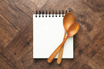 Blank recipe book and spoons on wooden table, top view. Mockup for design