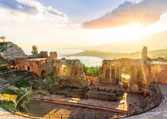 Obraz premium Panoramic view of a beautiful sunset in Ancient Theatre of Taormina in Sicily with antique italian town and mountain sunset on background. Holidays and sightseeing in Italy