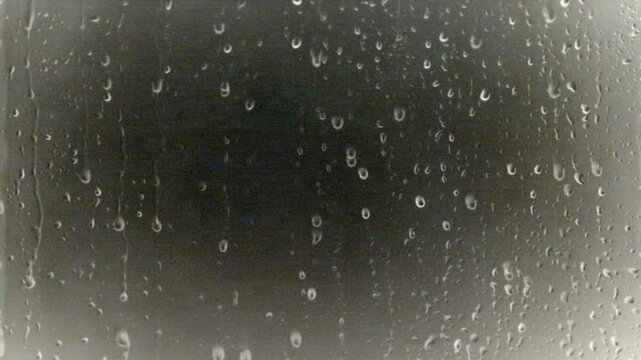 Video of raindrops flowing slowly on the surface of a window glass, creating a calm and melancholic atmosphere. Suitable for rainy background, sad mood, or weather visual effects. 4k