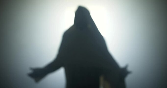 Silhouette of resurrection of Jesus Christ inside the tomb, in bright light, raising his hands in dramatic, cinematic slow motion. Perfect for Easter resurrection visual.