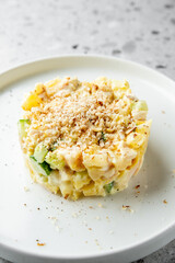 A creamy pasta dish layered with chopped vegetables and topped with a golden, crunchy breadcrumb crust, elegantly presented on a simple white plate.
