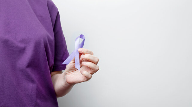 Purple ribbon held by a person in a purple shirt, symbol of support. Purple Epilepsy Awareness Day