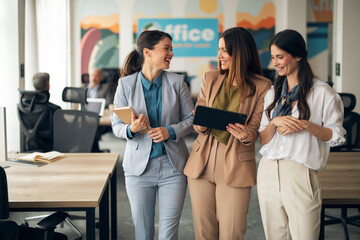 Three Female Professionals Collaborating and Smiling in a Modern Office Setting