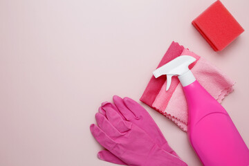 Pink cleaning supplies including rubber gloves, spray bottle, sponge, and microfiber cloths. Household cleaning and hygiene concept