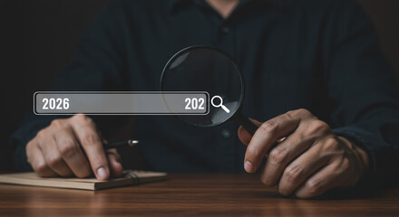 Planning 2026 A focused search for future trends using a magnifying glass on a dark wooden desk with