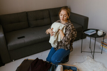 A Caucasian woman in her late 20s with blonde hair tied in a ponytail sitting on the floor in a...