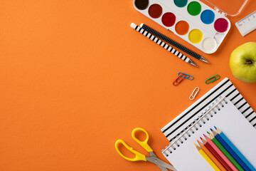 A vibrant arrangement of school and art supplies on an orange surface, including pencils,...