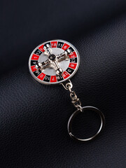 close up of silver metal casino roulette keychain on dark  background