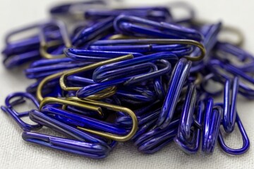 Colorful blue and gold paper clips scattered on a white surface for organization and office supplies