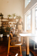As the caf? worker wipes down the table, she is distracted by the enchanting view of the sunny street outside the large windows.. A concept of business, pleasure, and contentment.